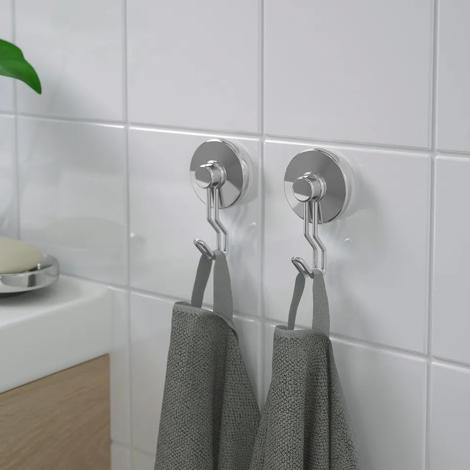Two metallic hooks with suction cups hang grey towels on tiled wall, showcasing their strong hold and space-saving design.