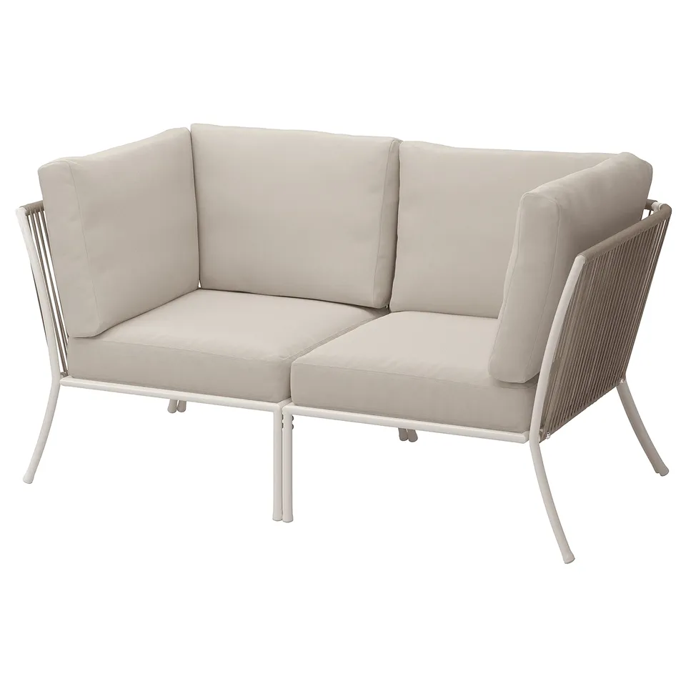 Modern beige outdoor corner couch with steel legs and beige cushions.