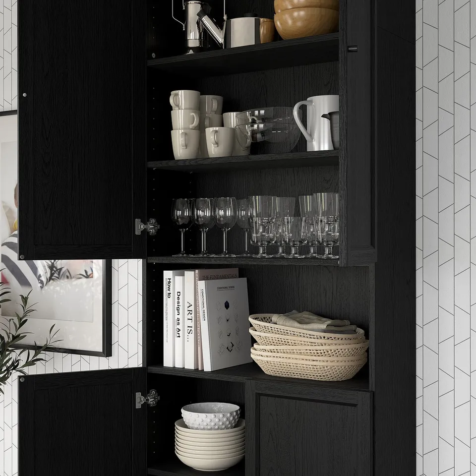 Wooden cabinet with open shelves displaying mugs, glasses, books, bowls.