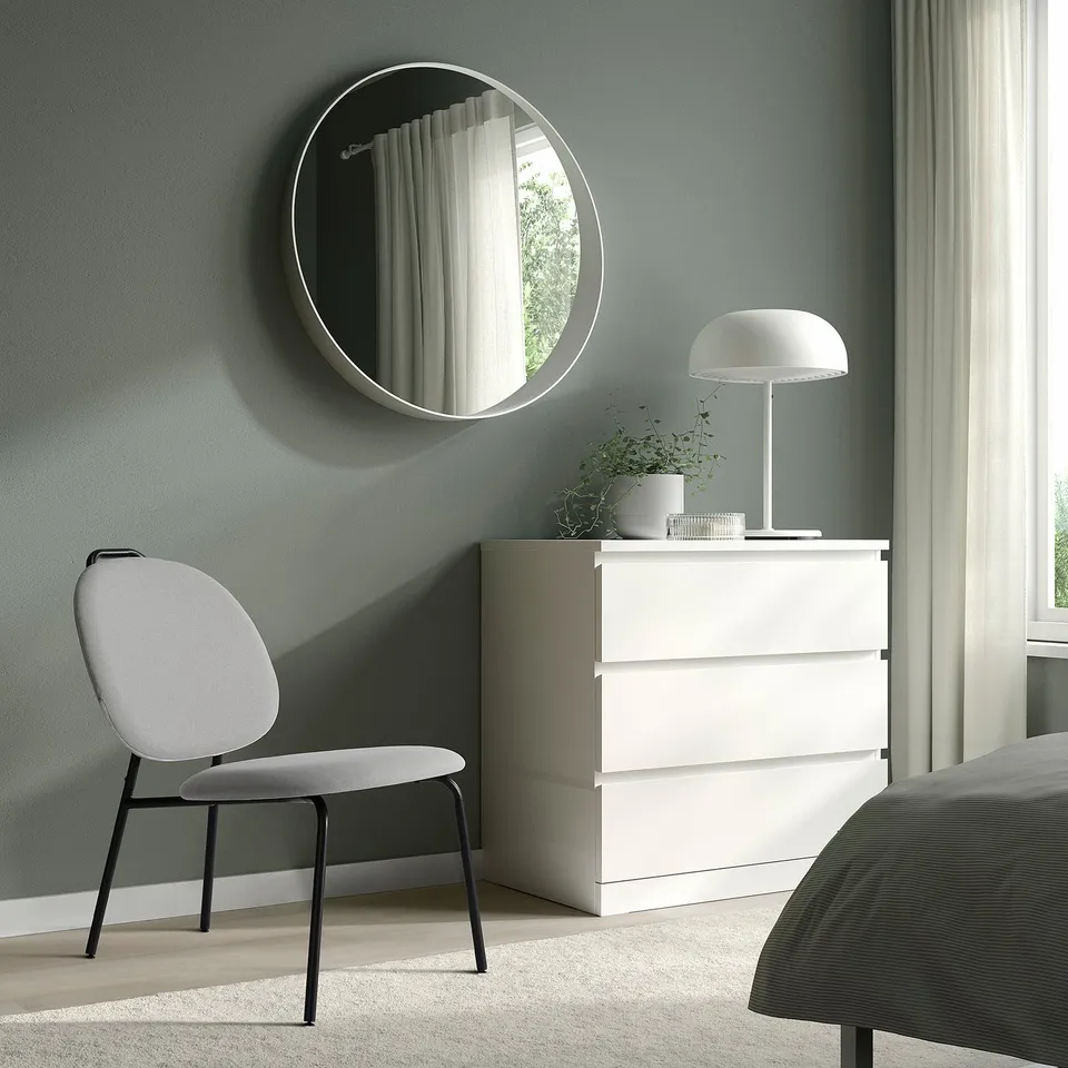 Modern bedroom with GÄVLE chair, dresser, mirror, lamp, plant.