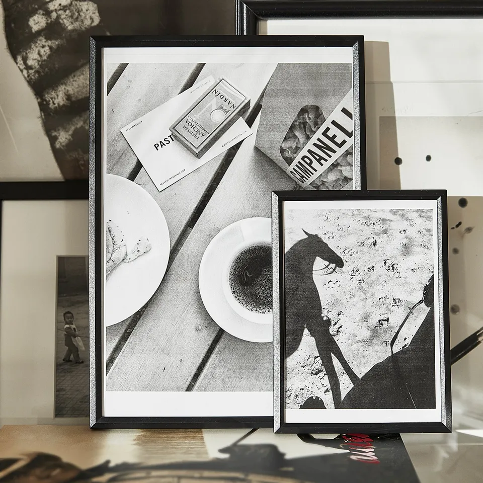 Black framed artwork on table. Includes two black and white photos; one of a horse and another of a table setting. Remaining images unseen.