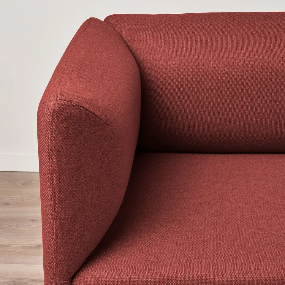 Close-up of a red fabric sofas armrest, showcasing its upholstery and cushioned quality.