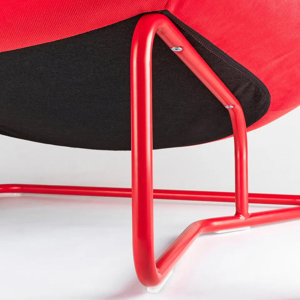 Red armchair with black fabric and metal base, showcasing sturdy construction and modern design.
