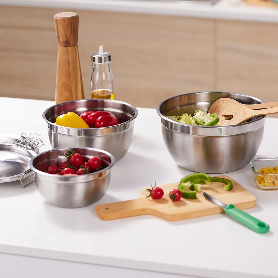 Stainless bowls with lids for food prep, serving, and storage. Various sizes nest for easy storage. Shown with fresh veggies and cutting board.