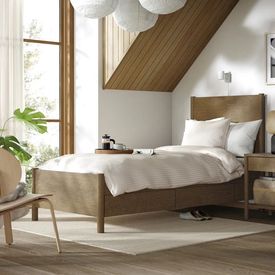 Cosy bedroom with light wood TONSTAD bed, white bedding, soft-close drawers, large window, small rug, and chair.
