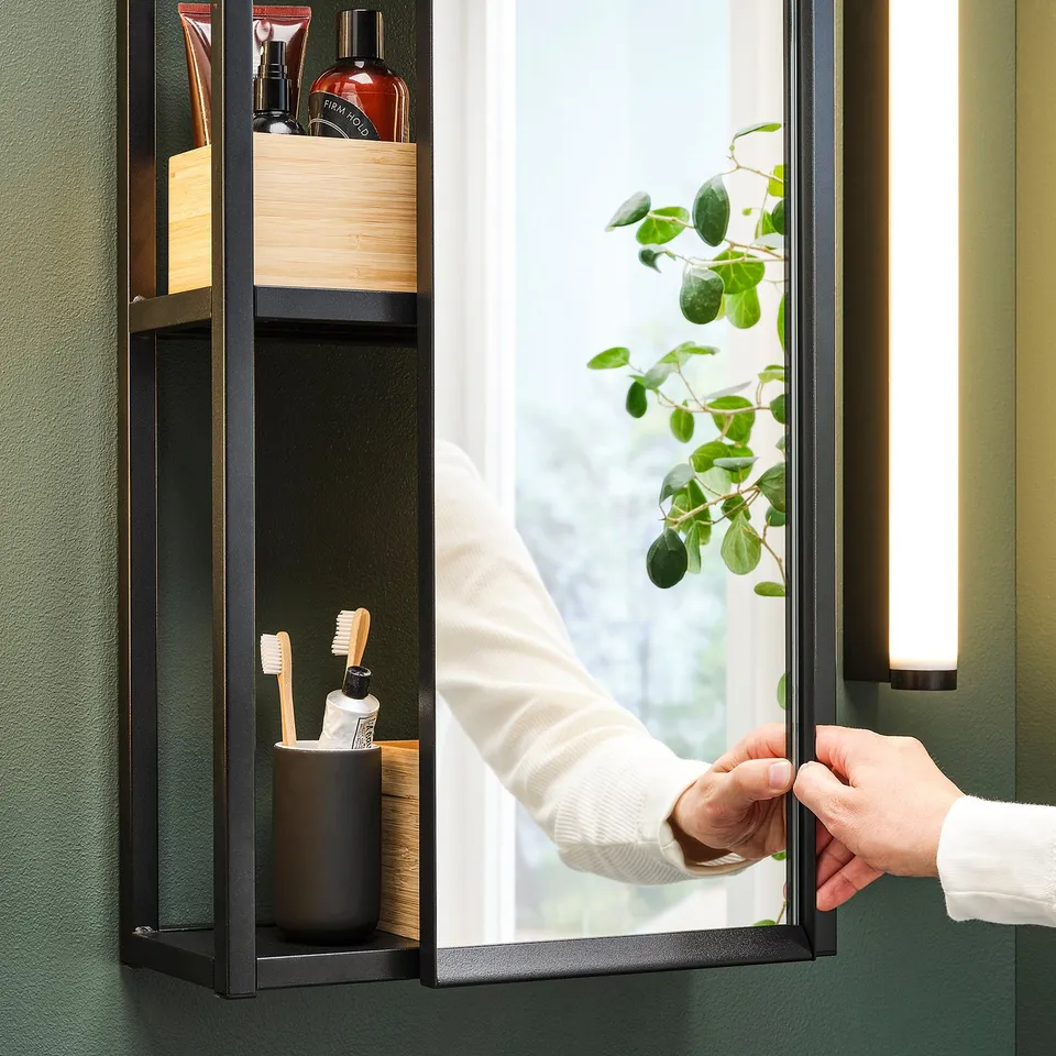 Hand opens mirrored cabinet revealing storage shelves with bathroom items.