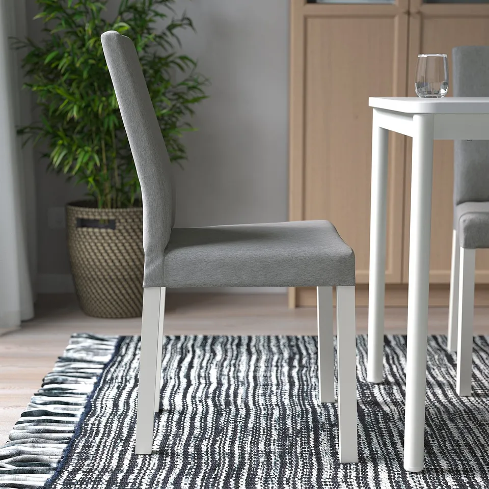 Chair with padding, metal legs, under table, grey, plant, glass.
