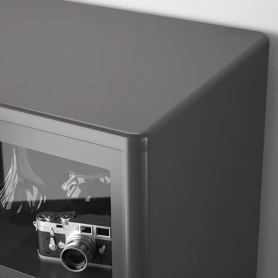 Black glass cabinet with sliding doors, showcasing vintage camera inside.