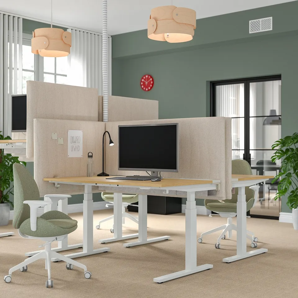 Modern office featuring MITTZON acoustic screens in beige, dividing desks with computers, and green chairs. Sleek design.