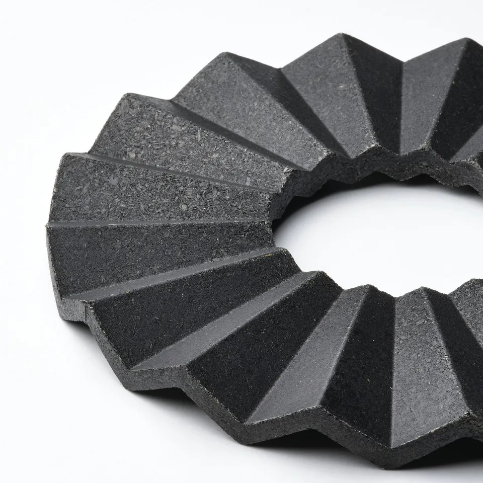 Geometric black bamboo trivet with sharp, angular design. Protective and stylish kitchen accessory.