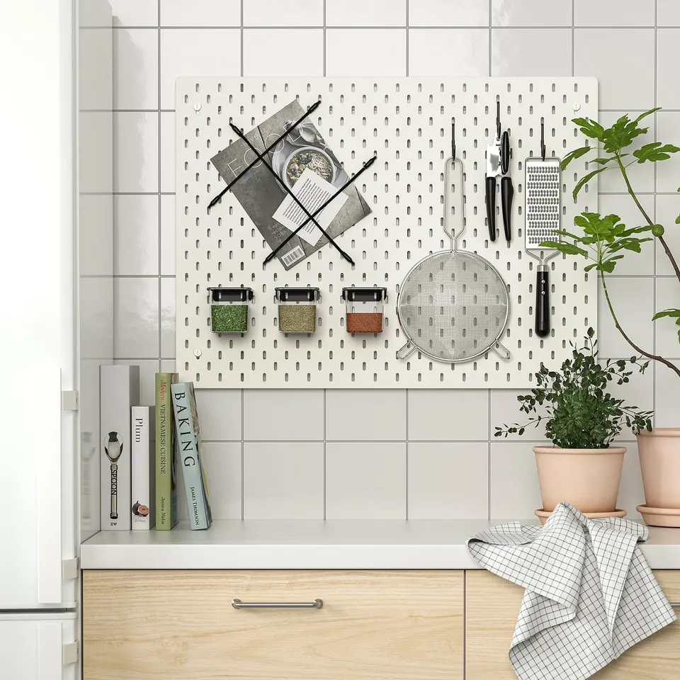 Kitchen pegboard with cooking tools, pots, and plants. Organised with SKÅDIS accessories.
