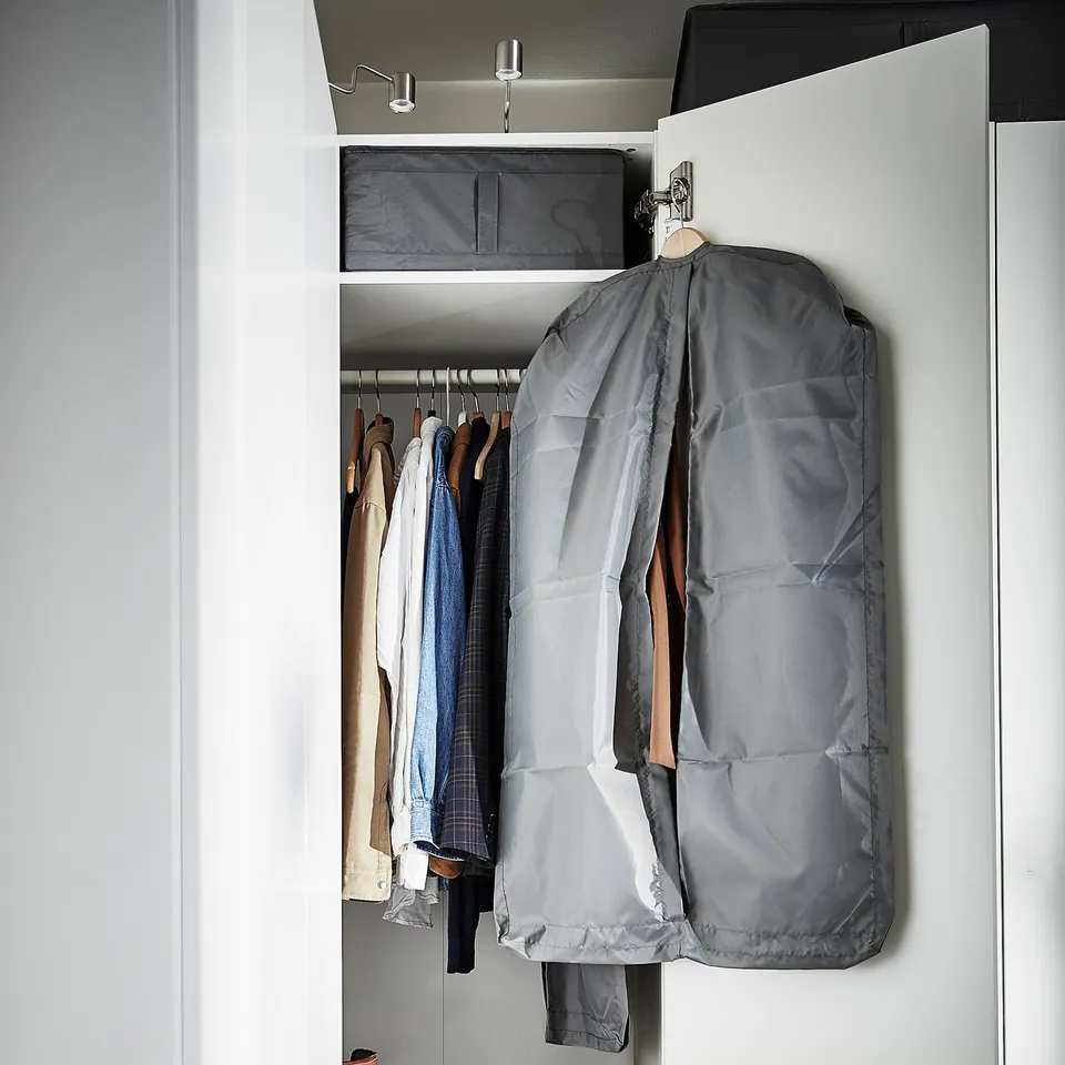 Open closet with clothes in grey SKUBB bag and other hangers.
