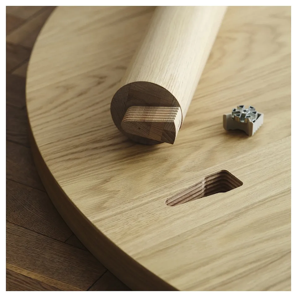 Oak dining table with cutout holding wooden tool and metal mechanism, showcasing functional storage feature.