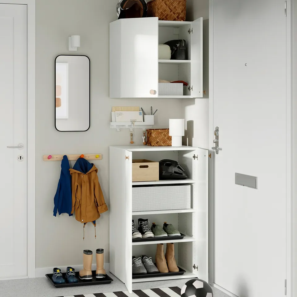 Modern entryway with white platsa storage unit displaying jackets, shoes, and accessories, featuring adjustable feet and wall-mounted design.