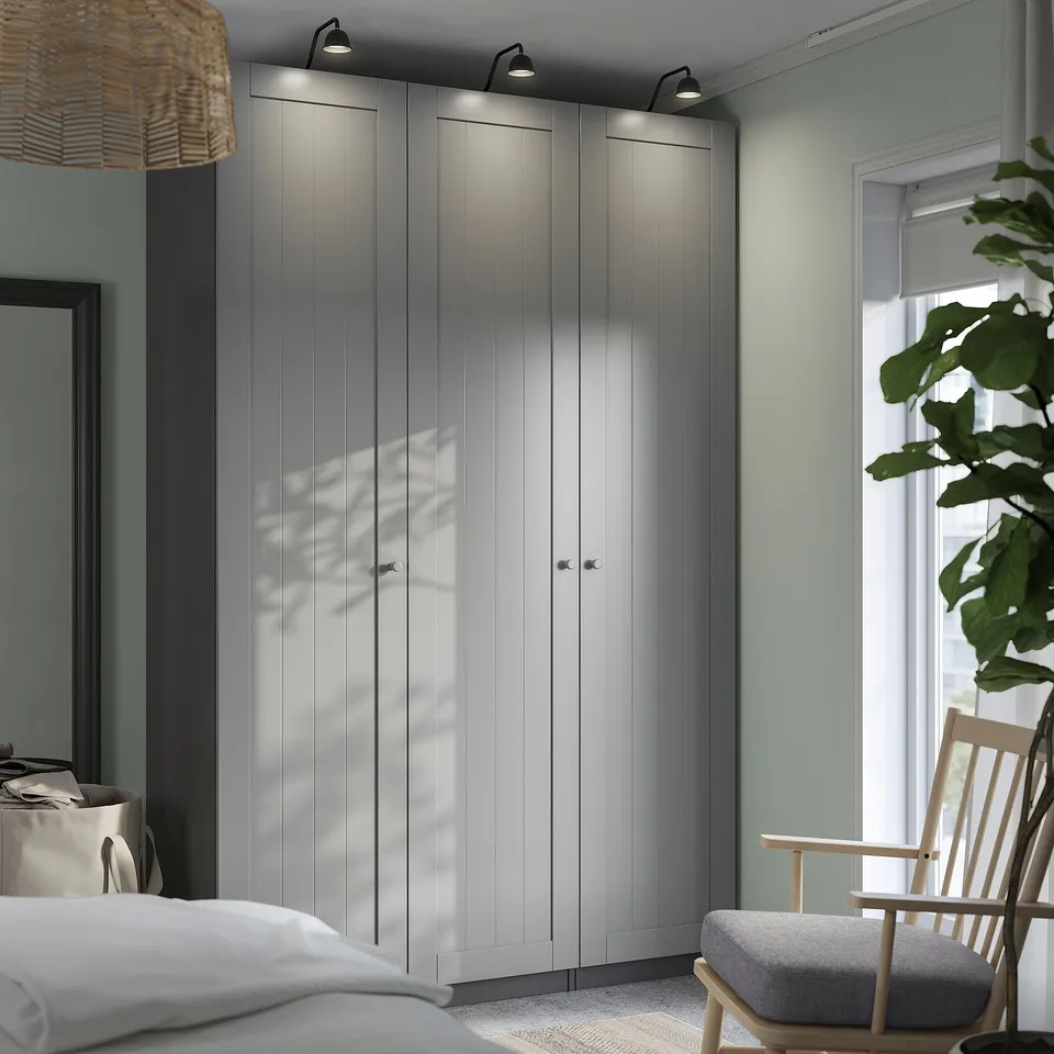 Modern bedroom with large grey PAX wardrobe, light wood chair and plant.