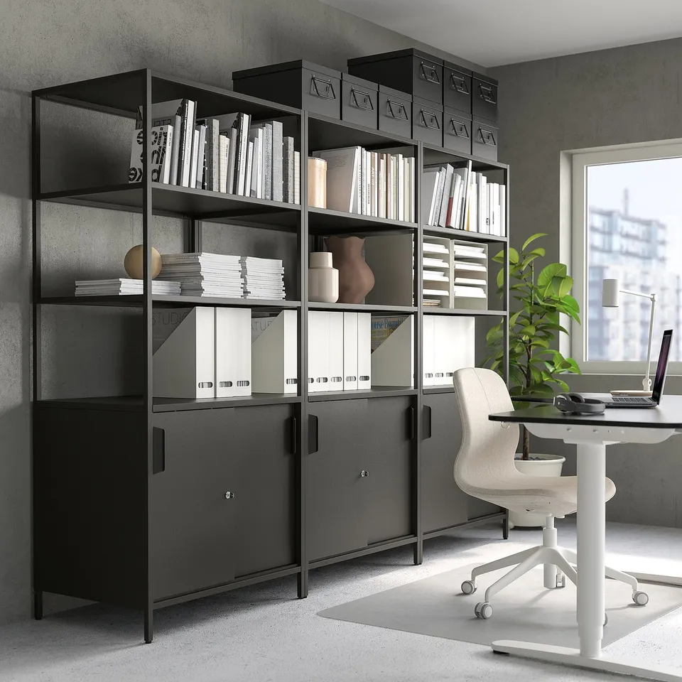 Modern black bookshelf with books, binders, decor, and office chair.