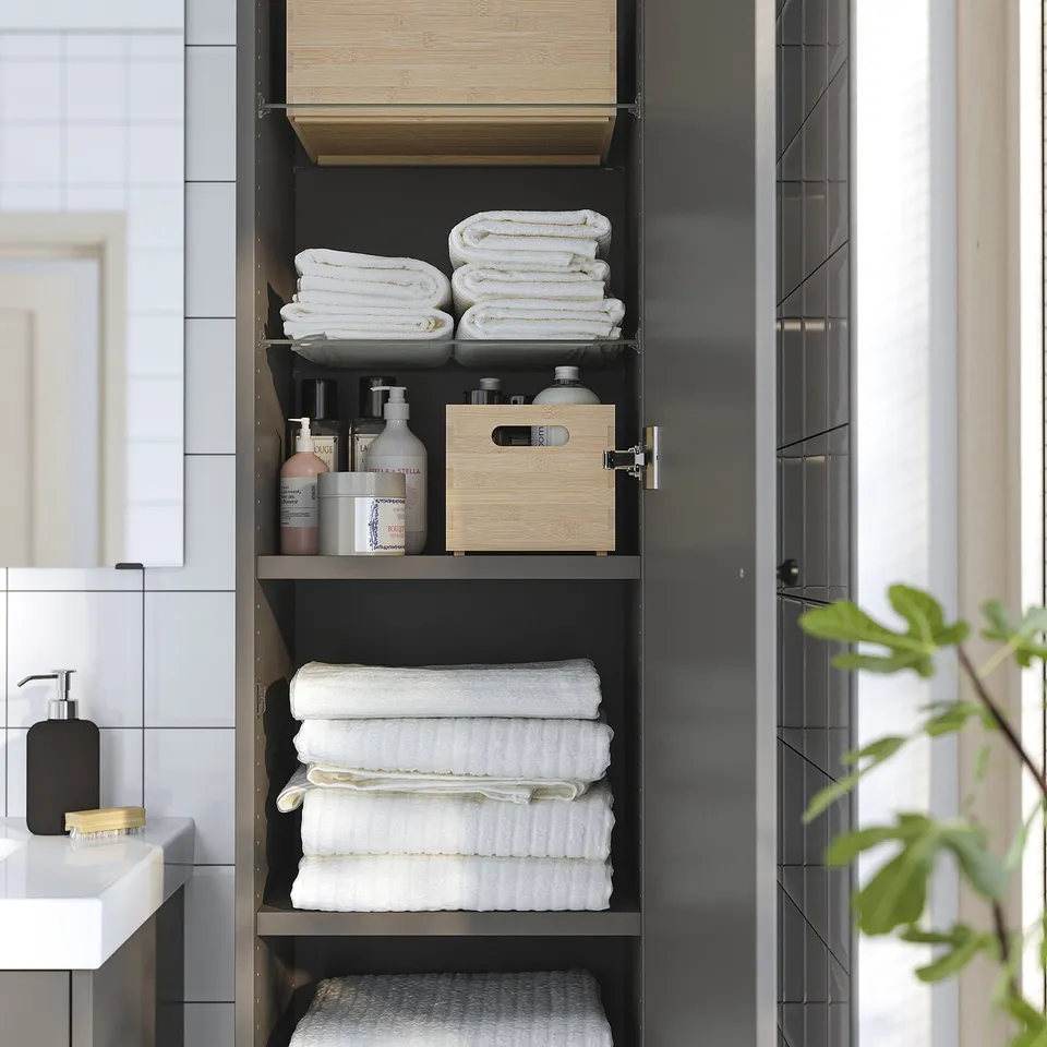 Open dark grey bathroom cabinet showing folded towels, toiletries, and wooden organisers on shelves.