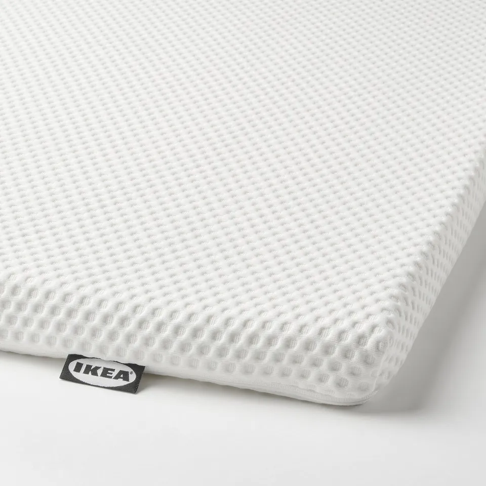 Close-up of IKEAs NORDBERGET mattress topper, featuring textured white surface with embossed pattern, showcasing quality and comfort.