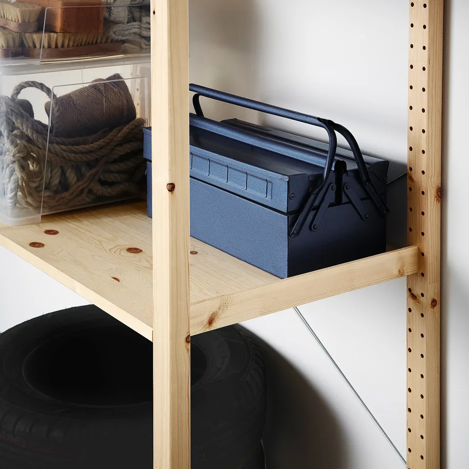 Wooden shelf unit with metal toolbox, rope basket, and tyre. Adaptable storage solution.