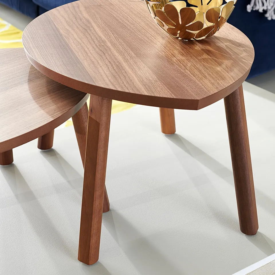Stacked wooden coffee tables with gold bowl, blue sofa.
