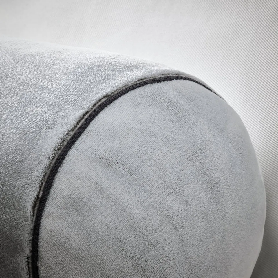 Close-up of a plush, grey cylindrical pillow with visible stitching, showing soft texture and quality craftsmanship.