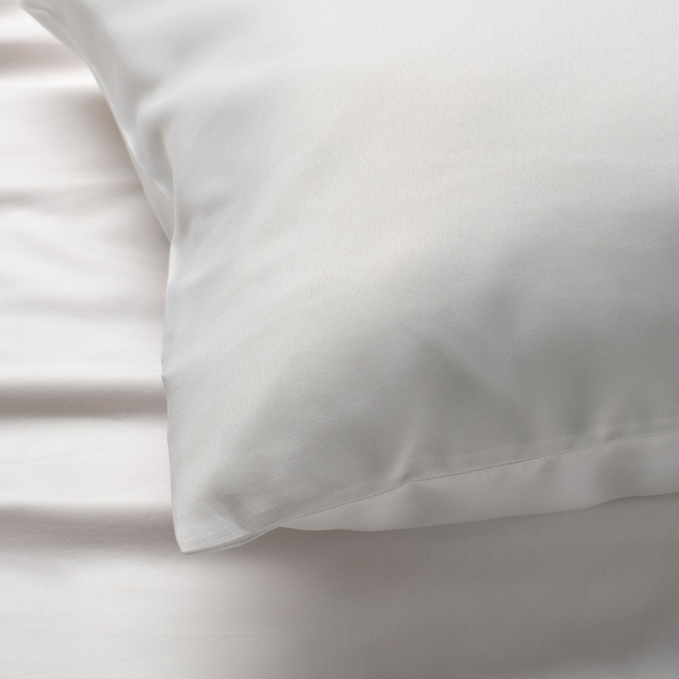 Close-up of smooth, white pillowcase. Soft, high-quality fabric feels comfortable for rest.
