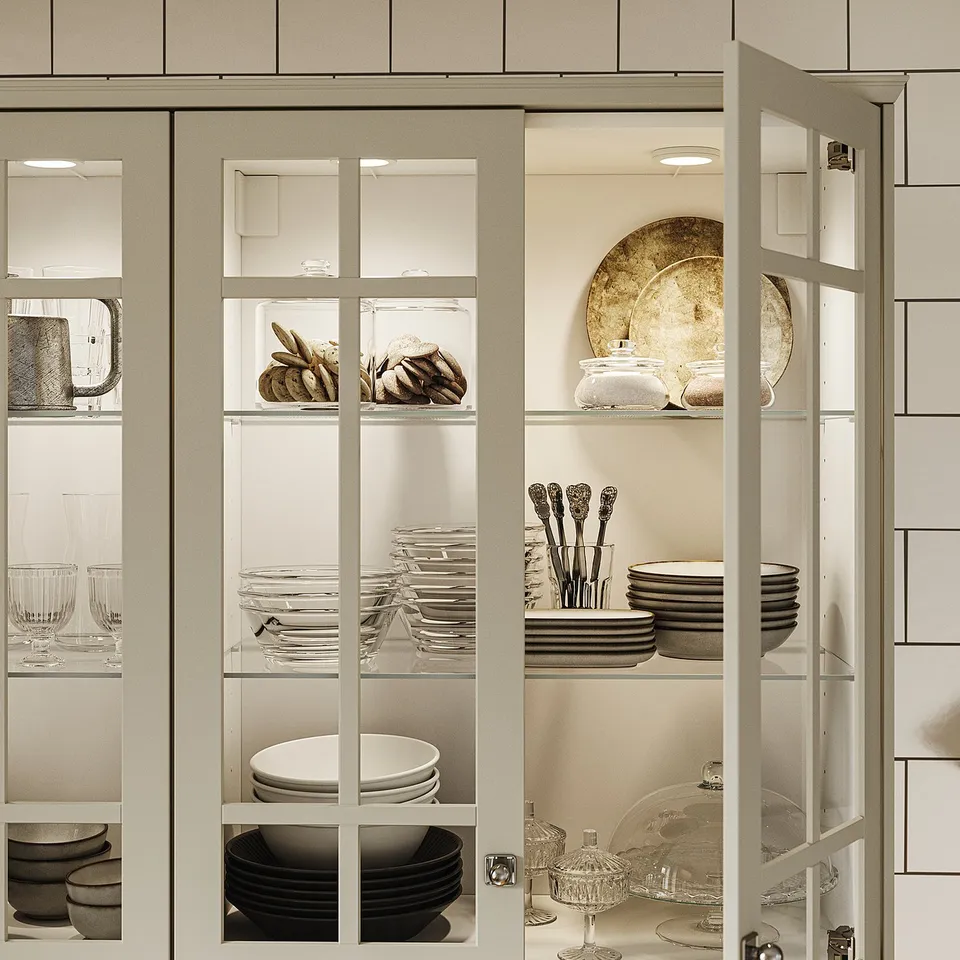 Glass-front kitchen cabinet with led lights showcasing plates, bowls, and cutlery, modern design.