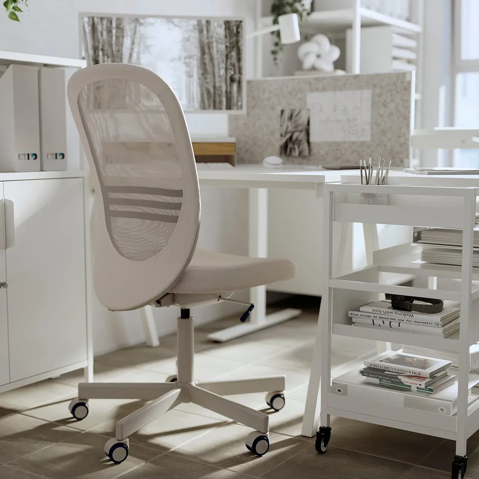 Modern home office: beige mesh-back chair, white desk, bookshelf, and storage cart.