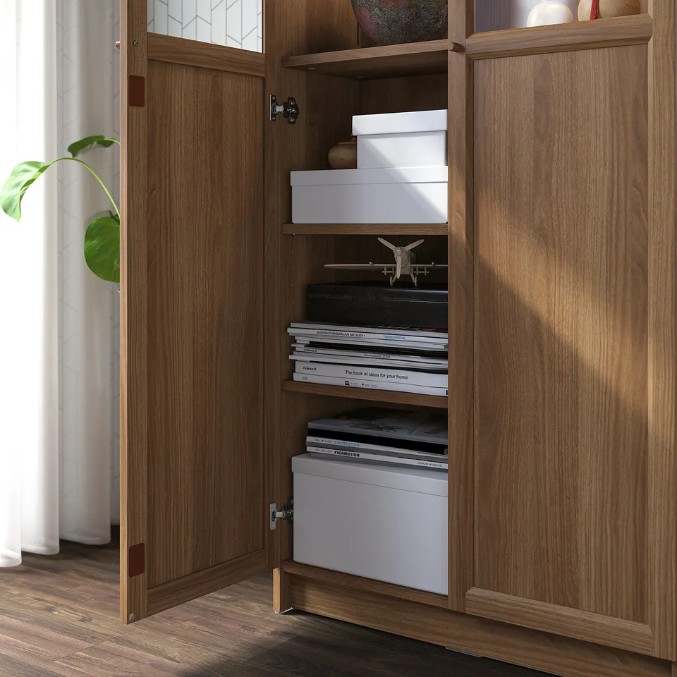 Wooden bookcase with glass doors open, displaying organised shelves holding white boxes and books.