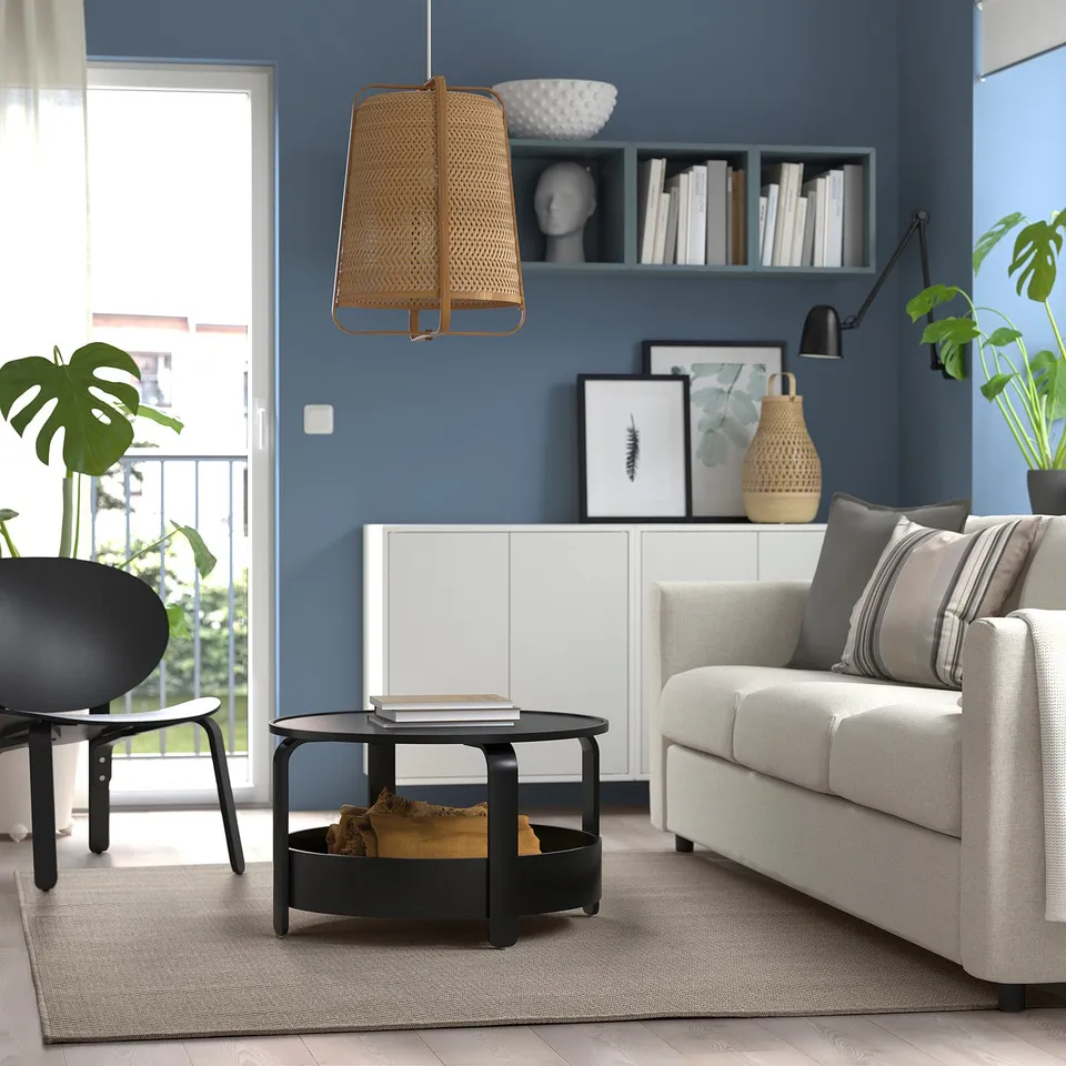 Modern blue living room with white sofa, black coffee table, wicker pendant, and plants.