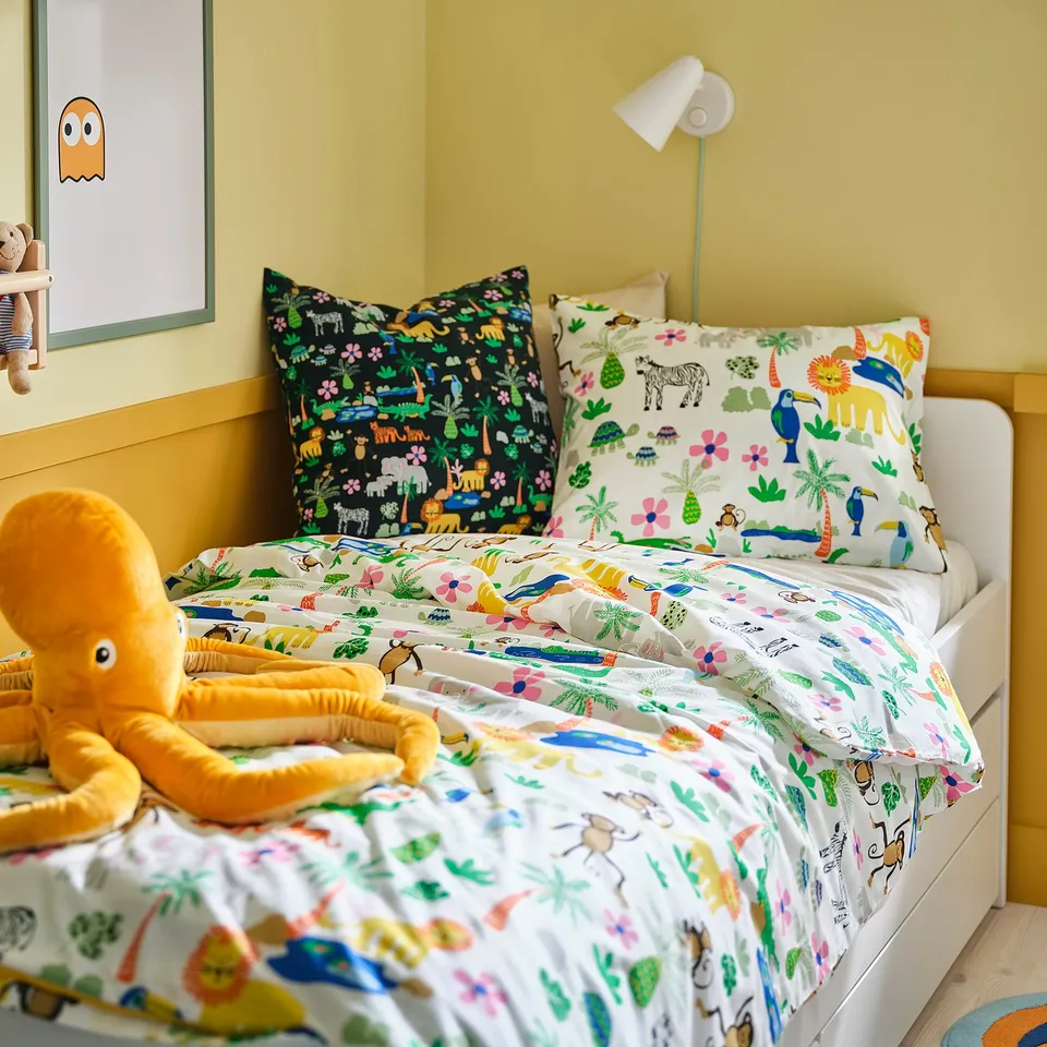 Yellow kids room with jungle bedding, cushions, and light.
