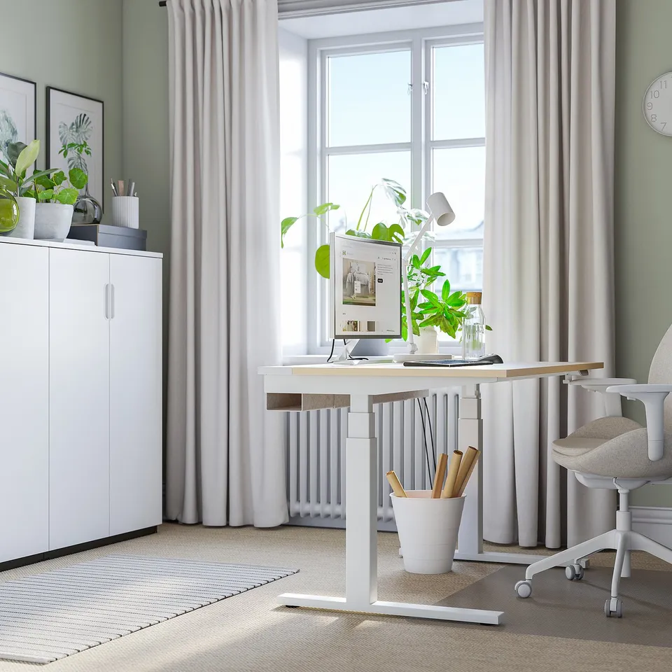 Home office with MITTZON sit/stand desk, monitor, plant, chair, cabinet, natural light.