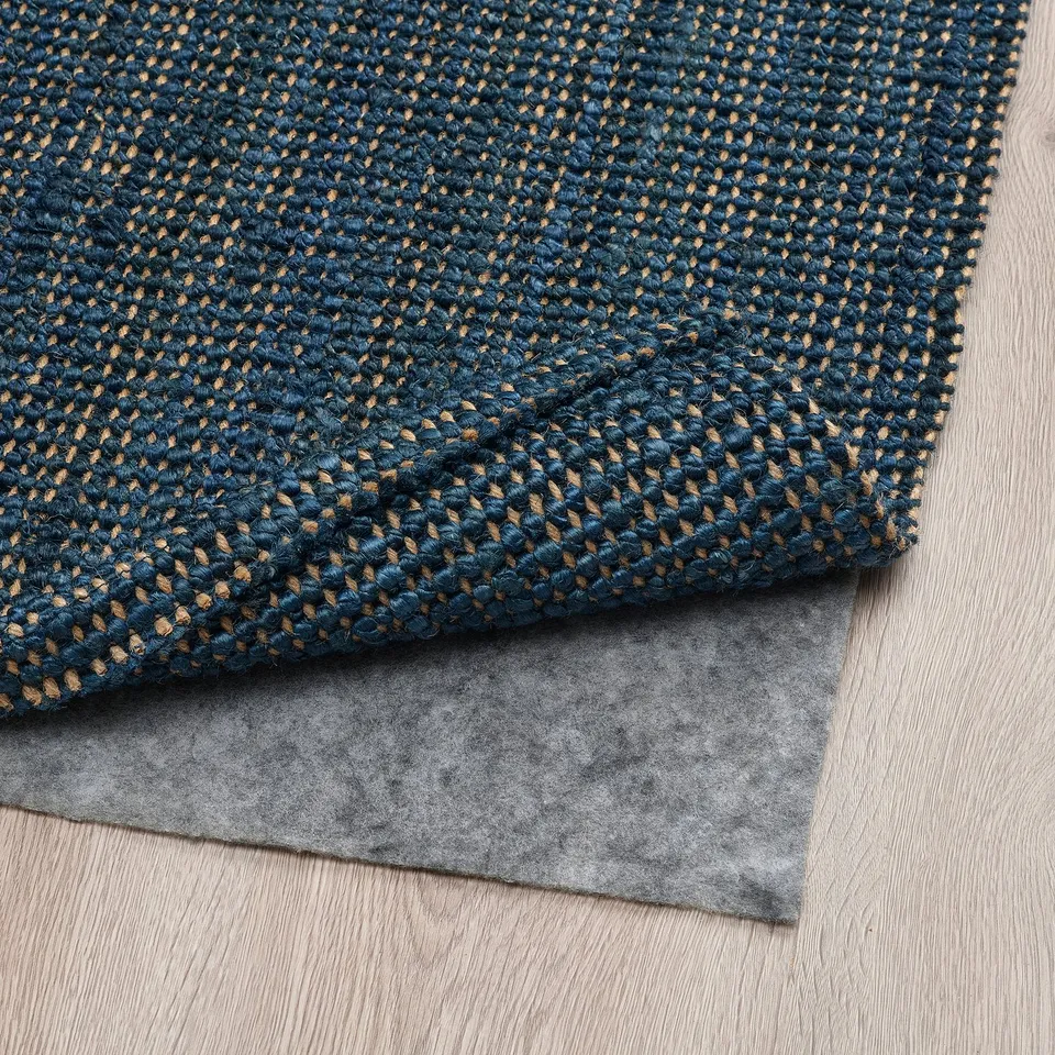Dark blue jute rug with anti-slip felt below, ideal for cosy flooring, shown on wooden floor.