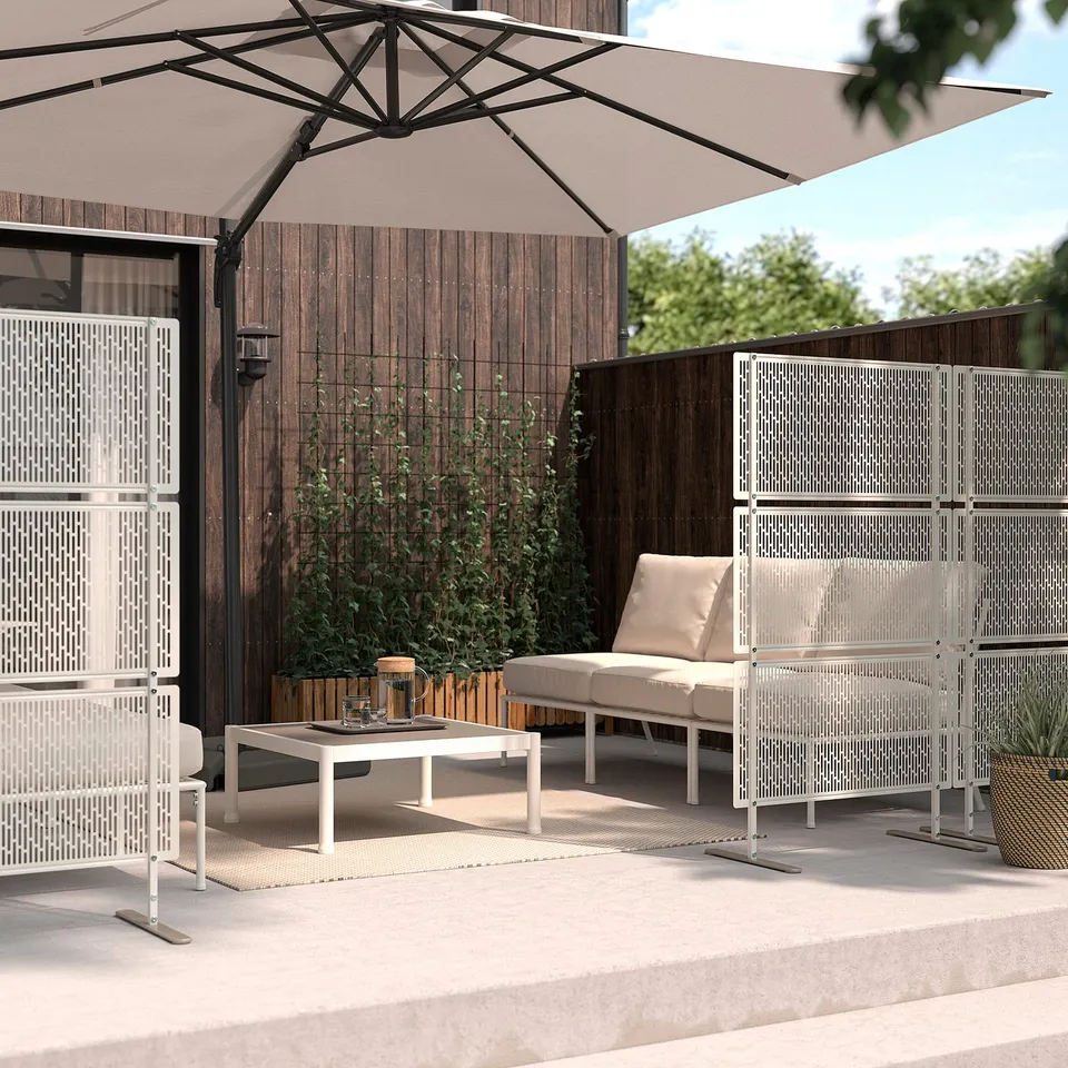 Modern outdoor area with LUNGÖN beige privacy screens, white furniture, and large umbrella. Concrete patio, wooden fence background.