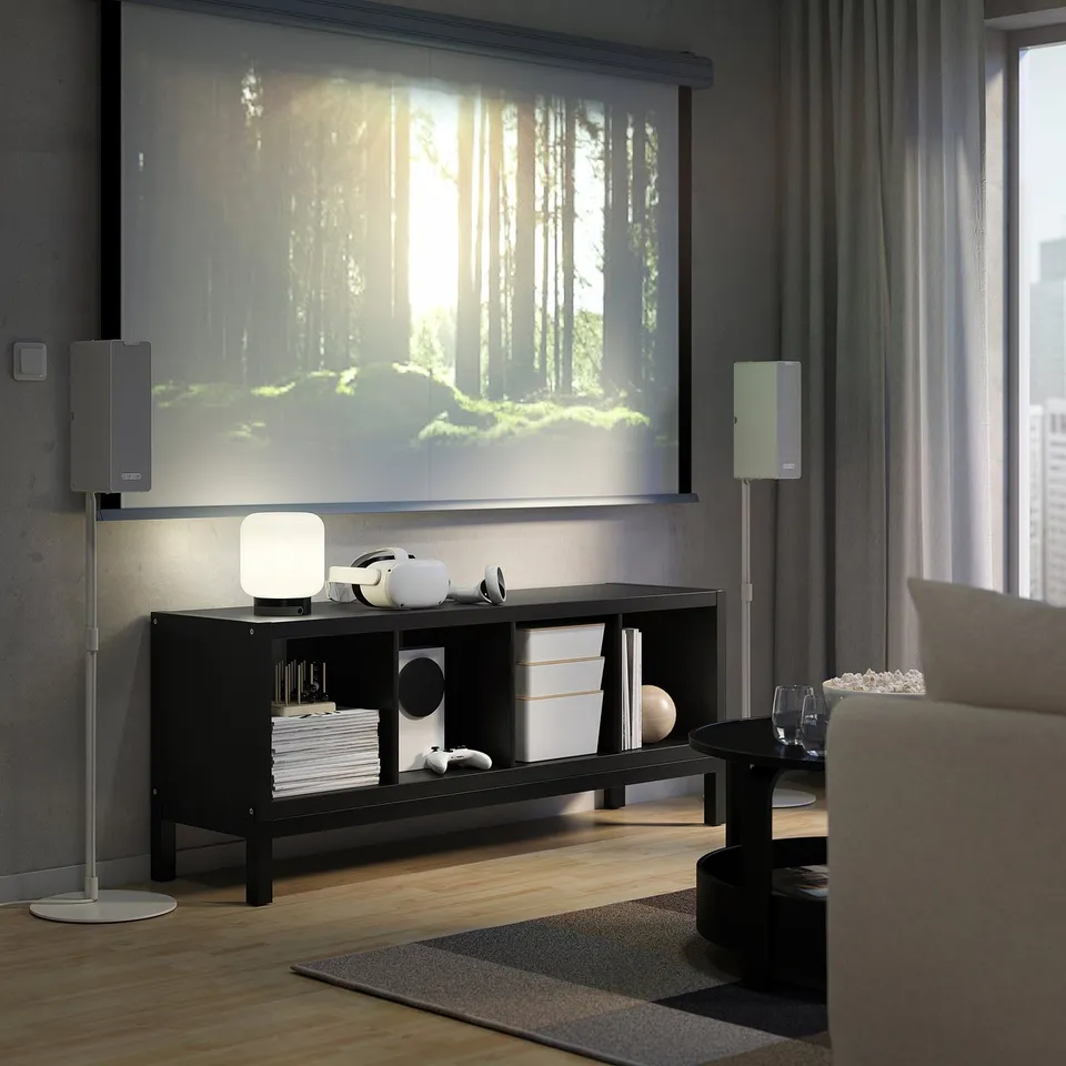 Modern living room with tv, KALLAX shelves, grey couch, speakers, and books.