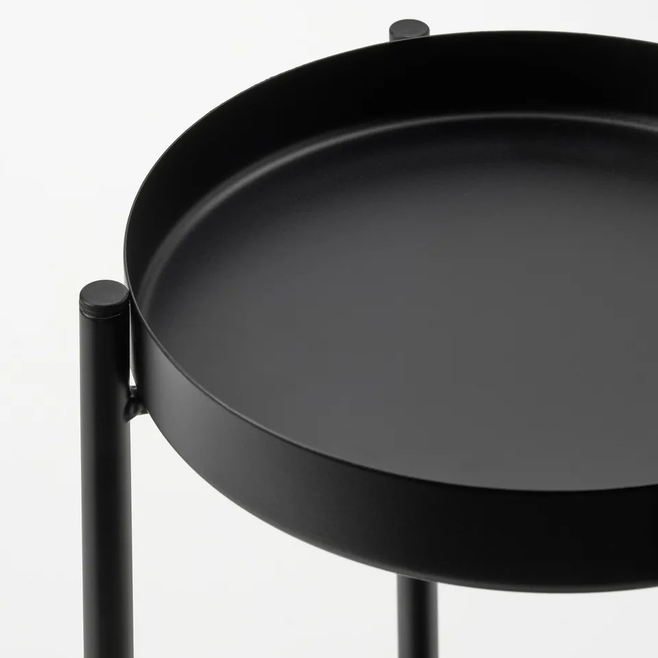 Minimalist black metal plant stand with round tray. Sturdy design displays plants elegantly.