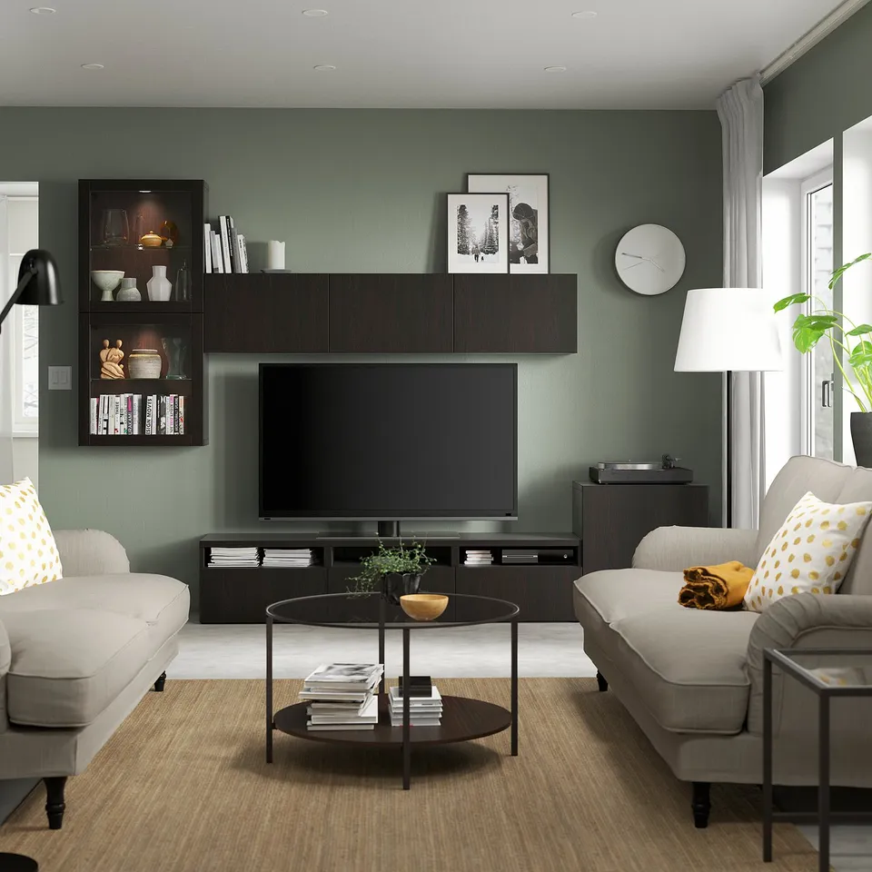 Modern living room with tv stand, shelves, yellow pillows, coffee table, lamp, clock, and plant.