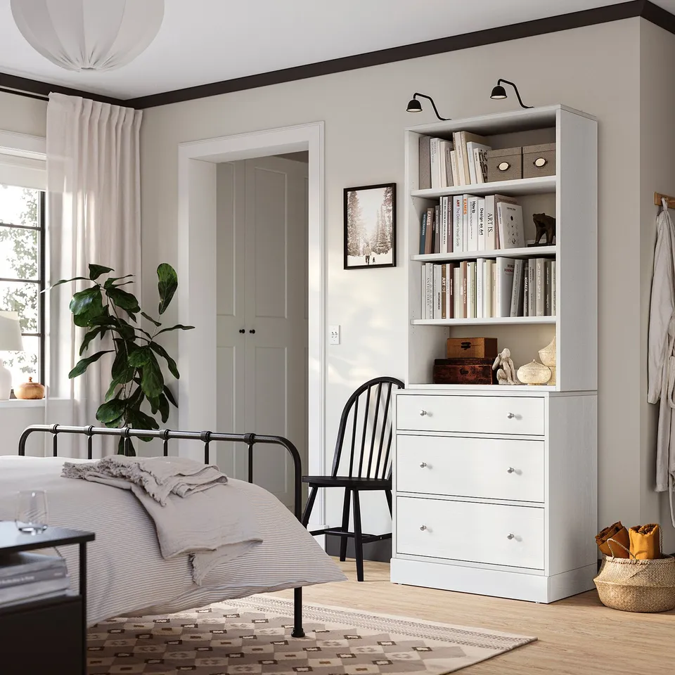 Cosy bedroom with HAVSTA chest & tall shelves, books, and minimalist decor.
