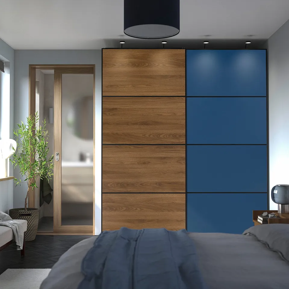 Modern bedroom with large blue-brown PAX wardrobe, sliding door, grey bedding, beside plant, and large black pendant light.