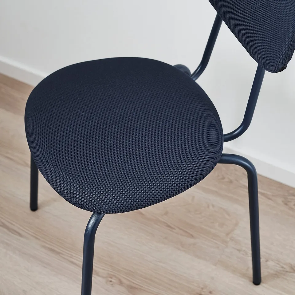 Dark grey upholstered chair with metal legs and curved back, placed on wooden floor.