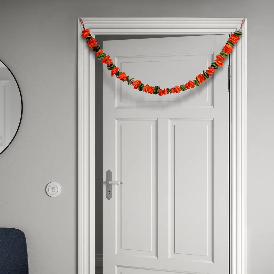 A festive garland with dried flowers hangs across a white door, adding colour and celebration.