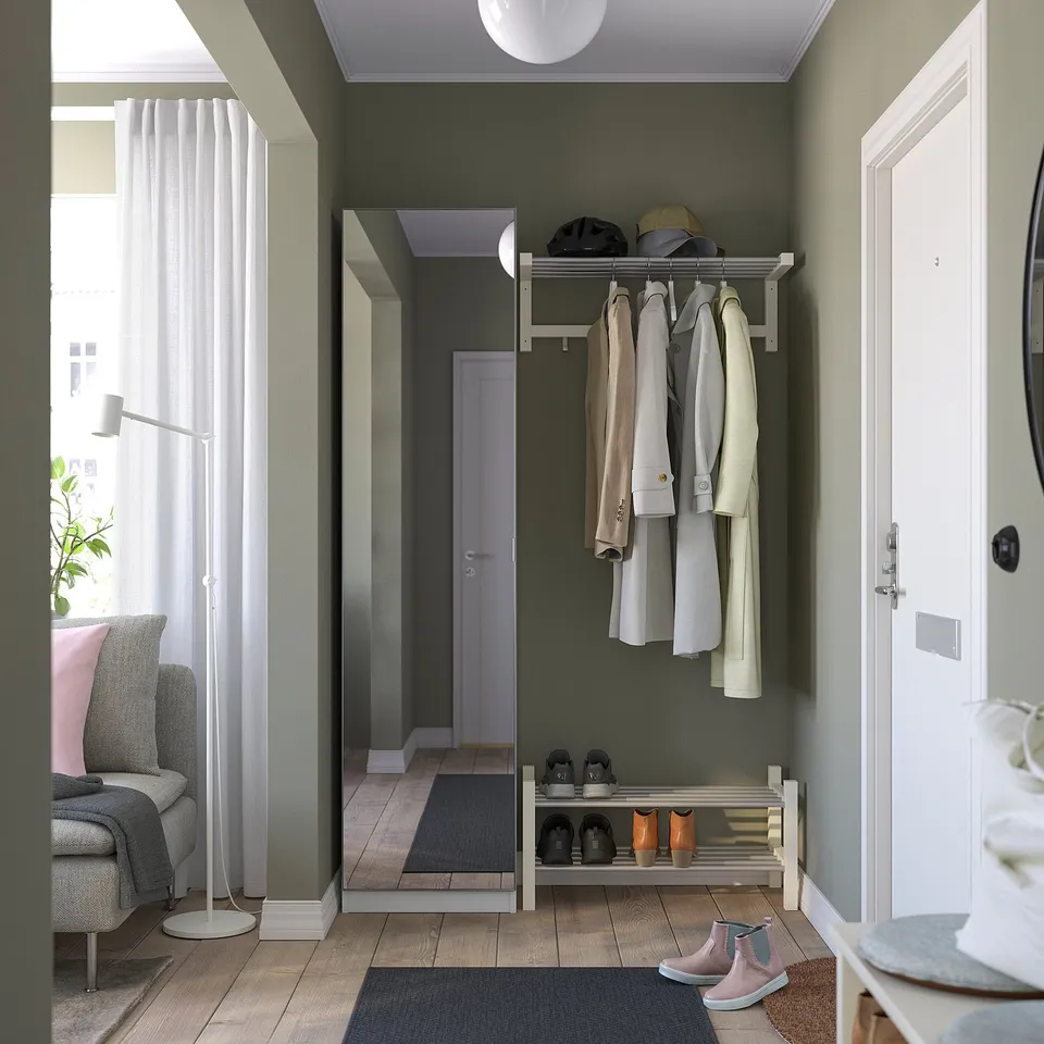 Modern entryway: coat rack, shoe rack, grey & pink rugs, chair by window, well-lit.