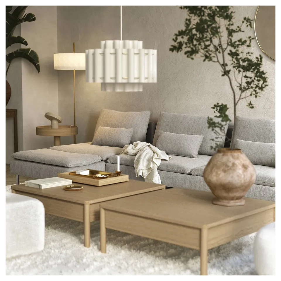 A modern, minimalist living room a light grey SÖDERHAMN sofa bed with wooden legs, a light-colored coffee table, and a hanging white lamp.