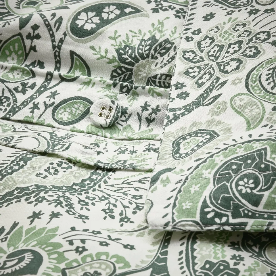 Close-up of paisley-patterned pillowcase. Decorative button secures duvet, using breathable cotton and smooth viscose blend.