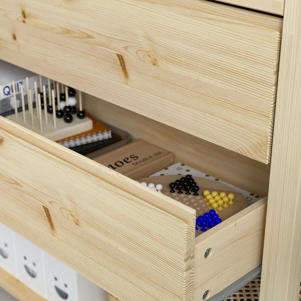 Light wood IVAR shelf with drawer open, revealing colourful game pieces.