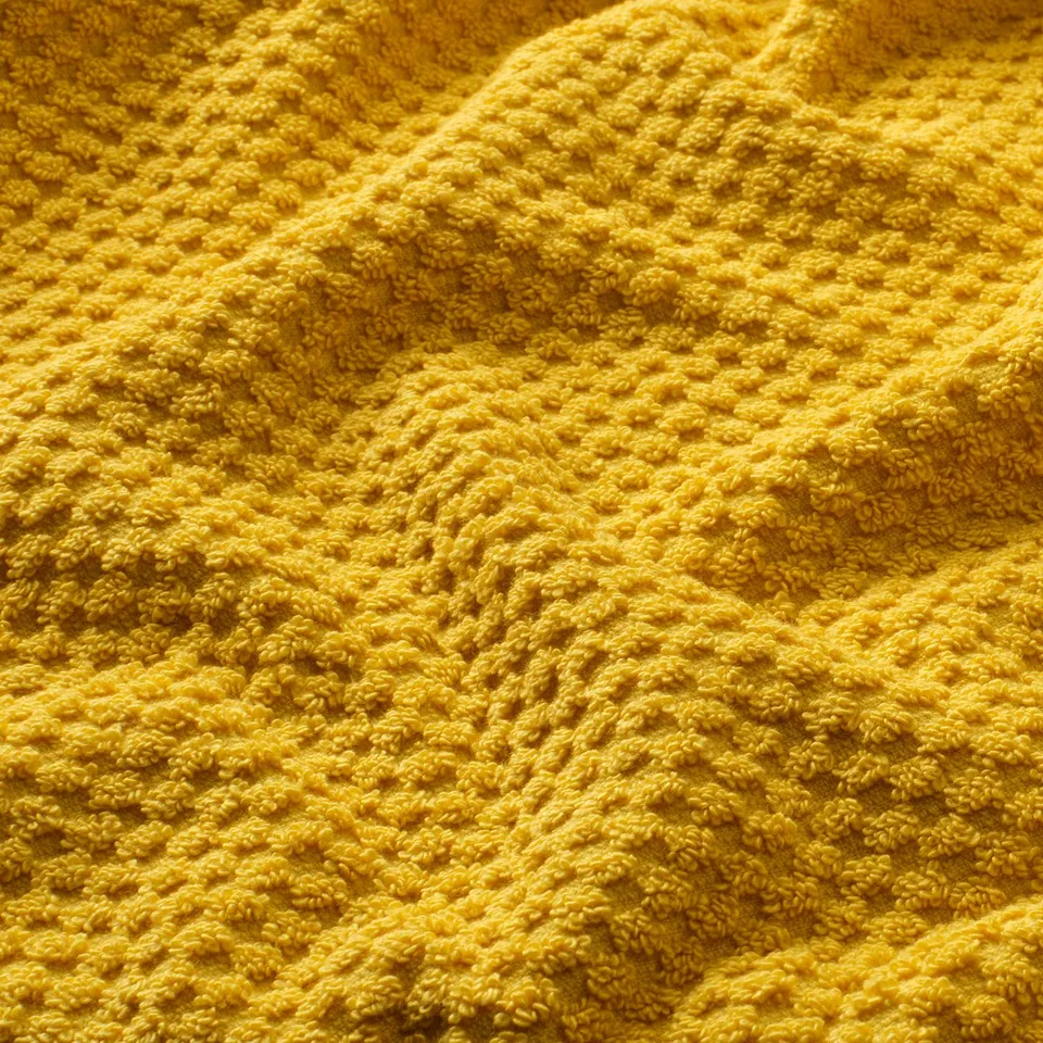 Bright yellow, soft, textured towel with intricate knit pattern, showcasing its fluffy and absorbent quality.