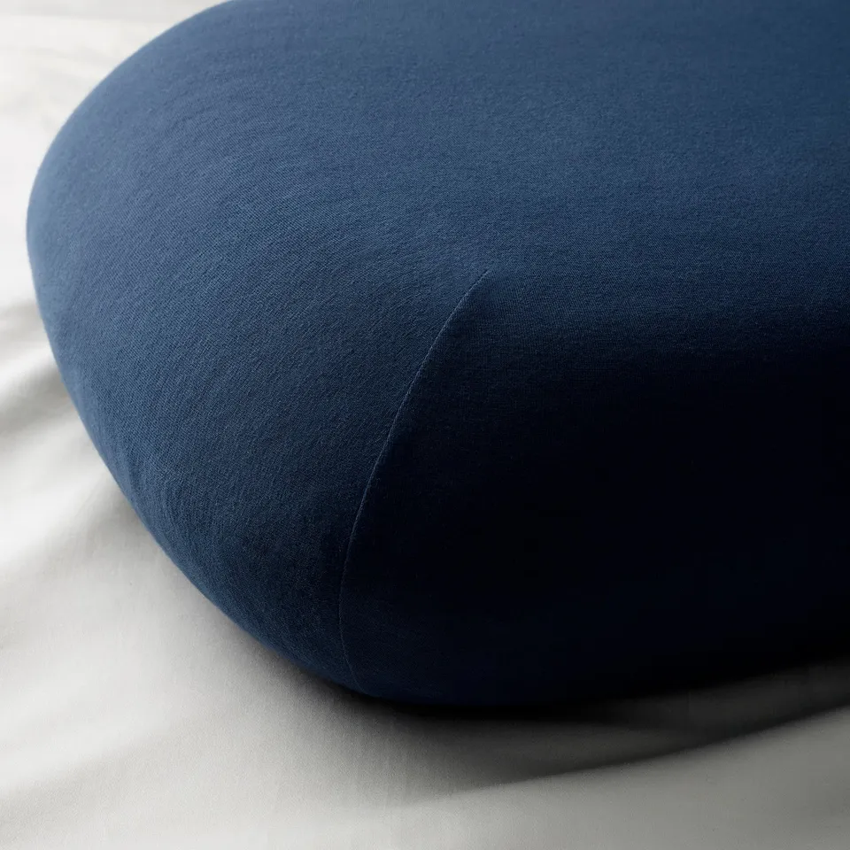Circular, dark blue, cushioned pillow with smooth fabric, likely made of cotton and elastane, for comfort and stretch.