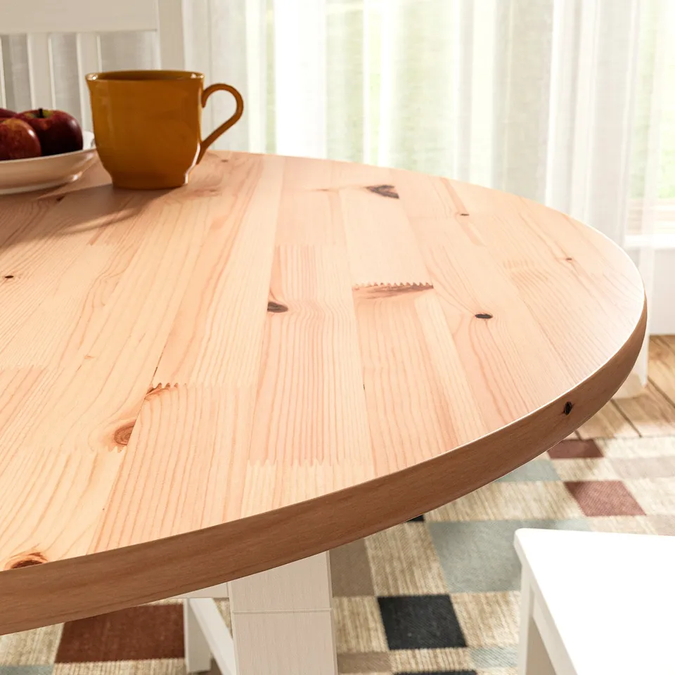 Round wooden table with light-colored grain, smooth edges, and a yellow mug on top.