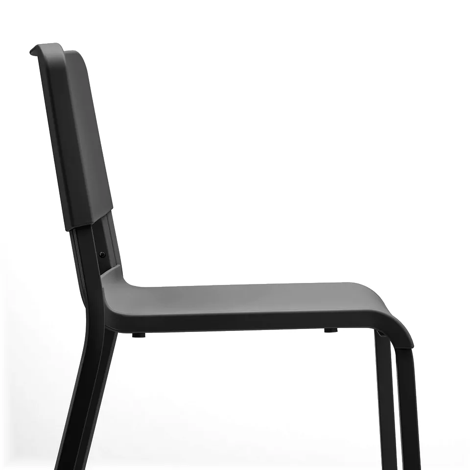 Black stackable chair with curved back and seat, sturdy metal legs visible, designed for comfort and durability.