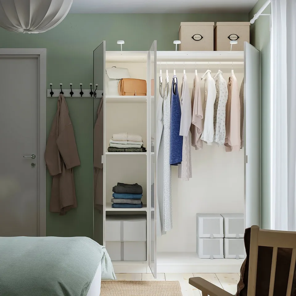 Modern closet with clothes, shelves, and towels. Mirrored doors expand space, reflecting light. Efficient wardrobe solution.